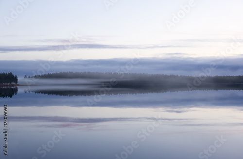 Magical view. Foggy landscape at the lake during night time in Finland