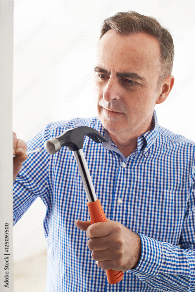 Mature Man Knocking Nail Into Wall With Hammer Stock Photo | Adobe Stock Mature Man Knocking Nail Into Wall With Hammer Stock Photo | Adobe Stock