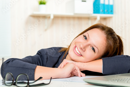 cute young girl posing in an office interior behind table
