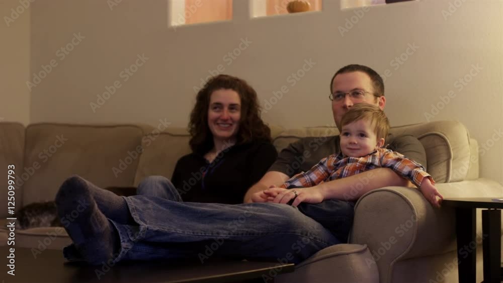 A family sitting down on the couch to watch television together A family sitting down on the couch to watch television together