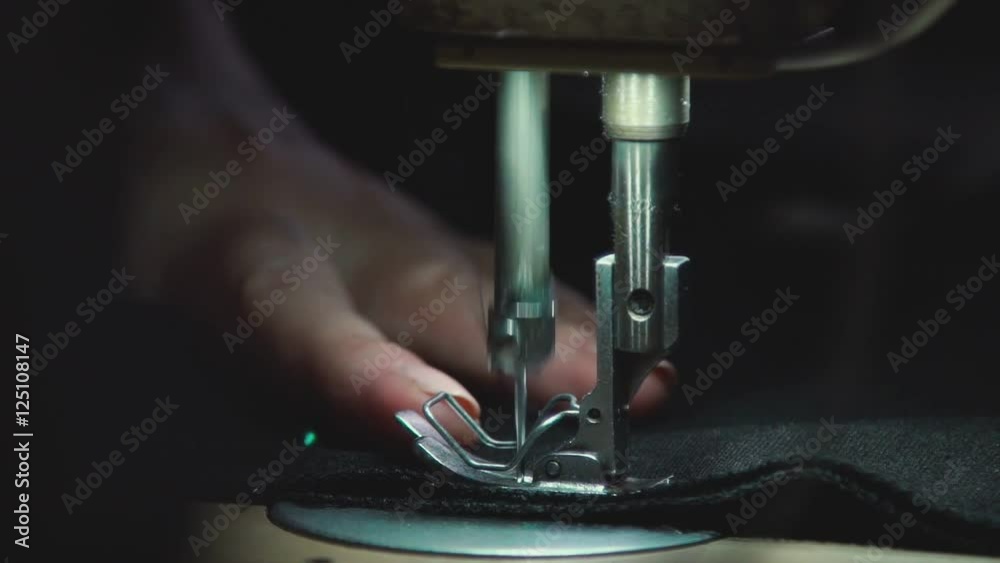 Sewing needle with thread at working sewing machine. Needle with thread stitching seam on fabric. Working sewing machine. Manufacturing equipment at factory.