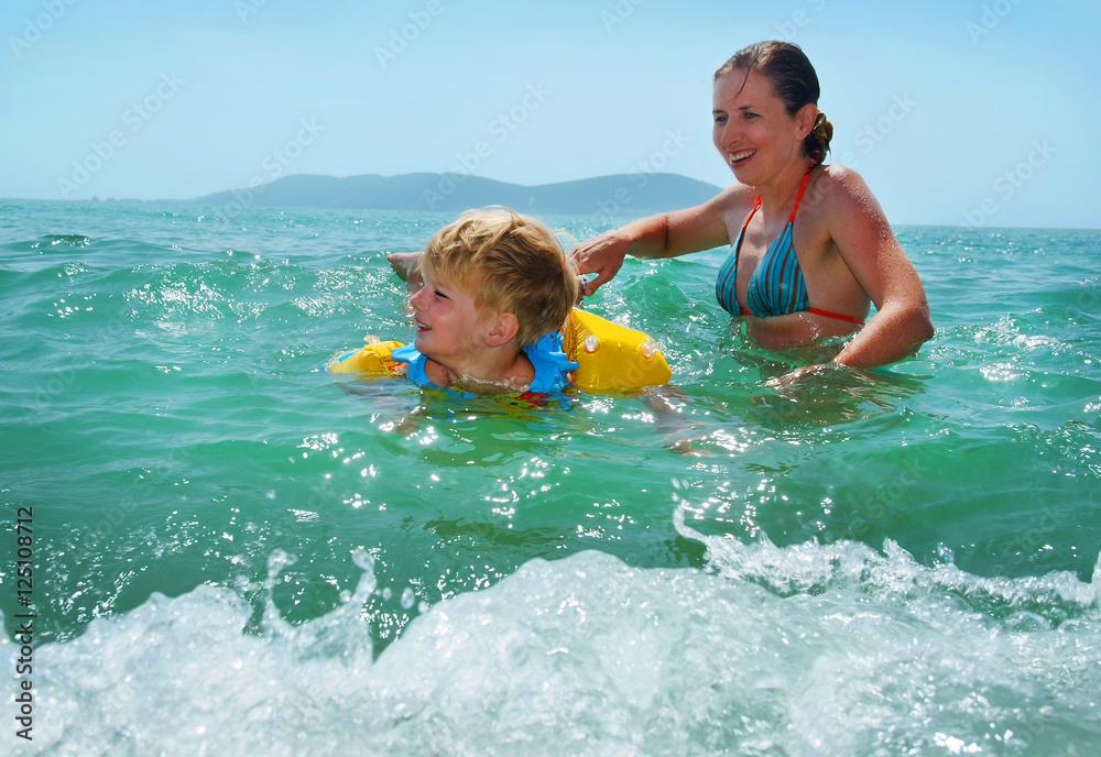 happy family of mother with kid in the waves on the sea beach happy family of mother with kid in the waves on the sea beach