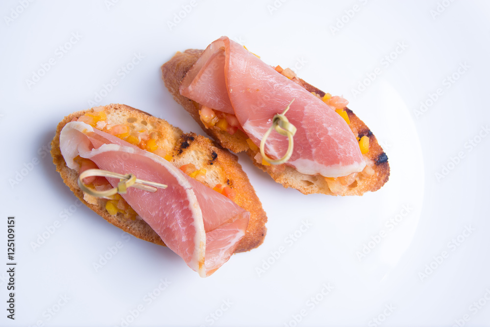 Bruschetta crostini with Parma ham, chopped tomatoes and peppers on a skewer. Italian cuisine