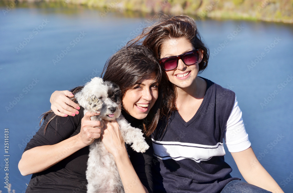two sisters hugging her small white poodle dog.Family time two sisters hugging her small white poodle dog.Family time