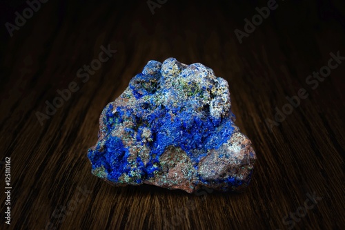 Multicolored rock with lazurite crystals on wooden board side view