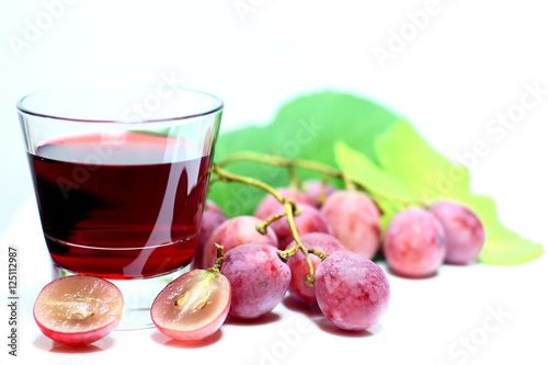 Red rose grapes bunch, glass cup with red natural organic house wine, and autumn grapes leaves isolated on white background.