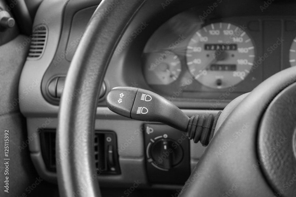 close up shot of a car's simple turn signal lever. black and white image. low key