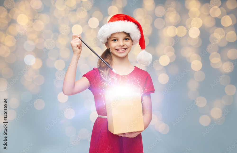 Obraz premium girl in santa hat with gift box and magic wand