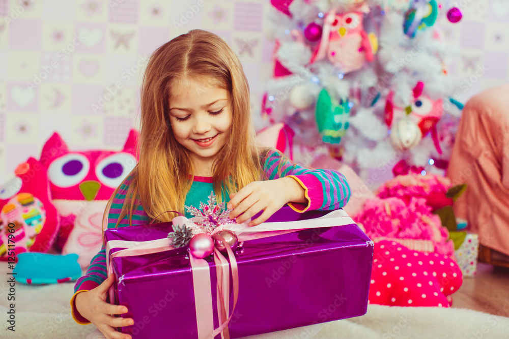 Blonde girl plays with Christmas present box Blonde girl plays with Christmas present box