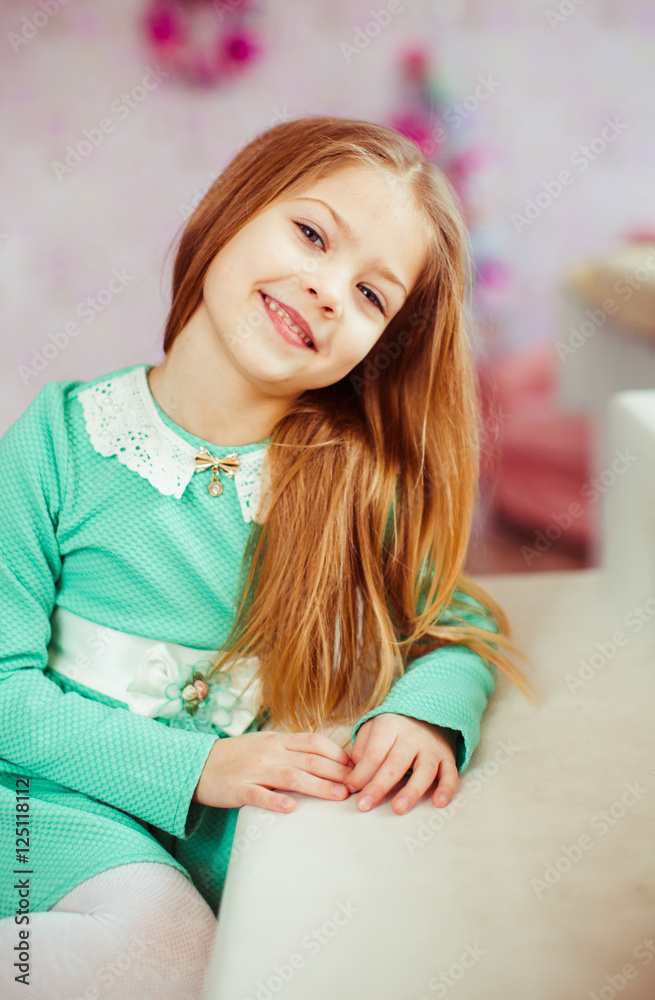 Blonde child in mint dress sits at the white table Blonde child in mint dress sits at the white table