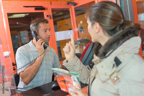 Woman trying to get attention of man in ticket office
