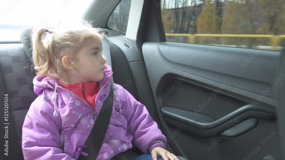 Little girl warm clothing looking out from car window.