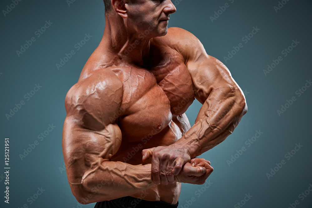 The torso of attractive male body builder on gray background.