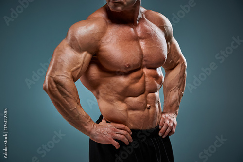 Фотография torso of attractive male body builder on gray background.