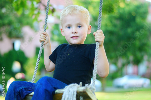 Adorable little blonde boy having fun at the playground.