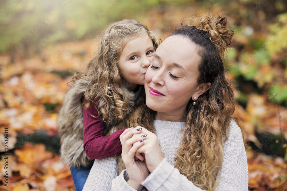 Fototapeta premium Young mother playing with her daughter in autumn park