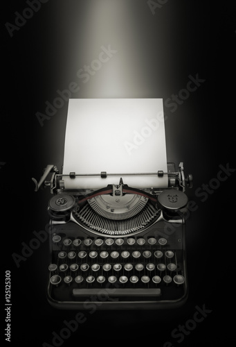 Ancient typewriter against black background. Light effect over white page