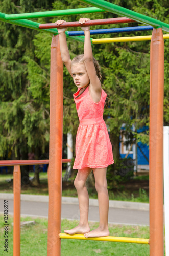 The girl in the pink dress on the horizontal bar climbing on playground
