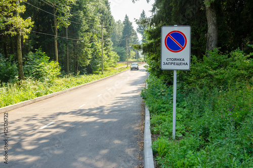 Traffic sign "No parking" on the forest road on which the moving car