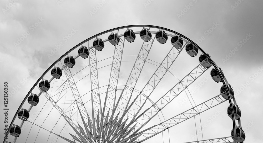 Ferris wheel on cloudy sky background black and white photo
