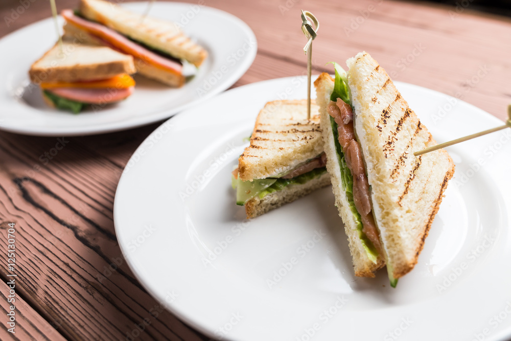 Club sandwich with salmon on white plate