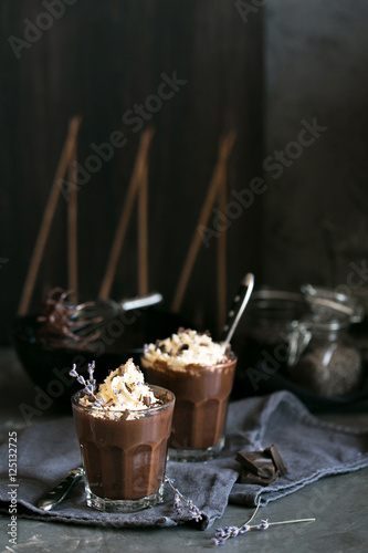 Two glasses of chocolate mousse with lavender topped with whippe
