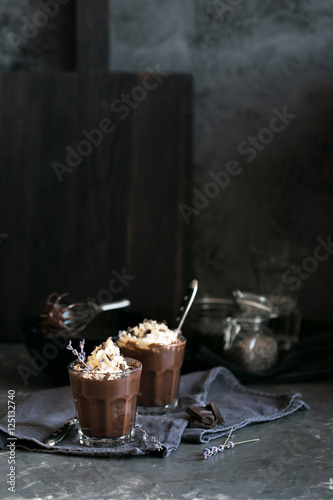 Two glasses of chocolate mousse with lavender topped with whippe
