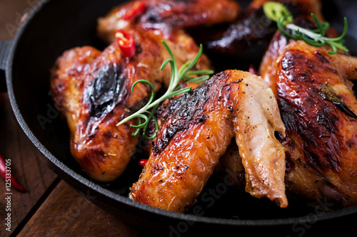 Baked chicken wings in pan on wooden table.