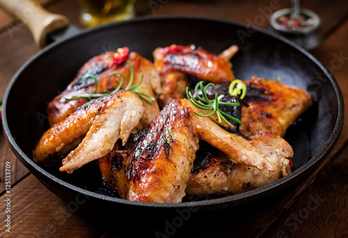 Baked chicken wings in pan on wooden table.