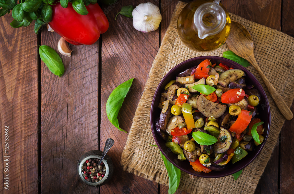 Hot spicy stew eggplant, sweet pepper, olives and capers with basil leaves. Top view Hot spicy stew eggplant, sweet pepper, olives and capers with basil leaves. Top view