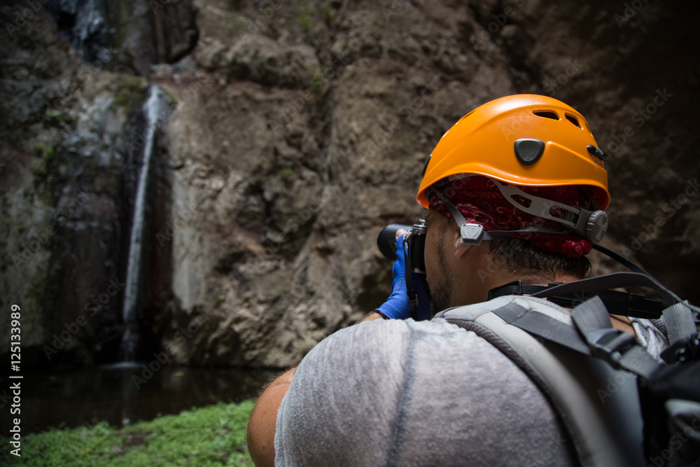 Backpacker man hiking and taking pictures of waterfall in Barranco del Infierno in Tenerife. Canary islands, Spain