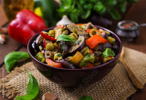 Hot spicy stew eggplant, sweet pepper, olives and capers with basil leaves.