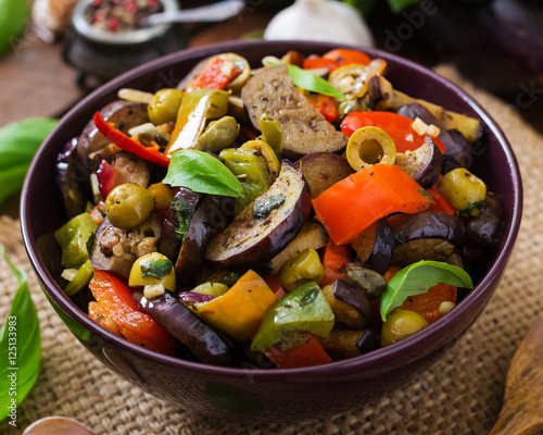Hot spicy stew eggplant, sweet pepper, olives and capers with basil leaves.