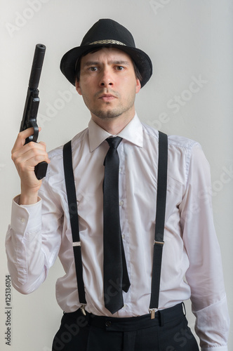 Young detective holds gun with silencer in hands. Isolated on white background.