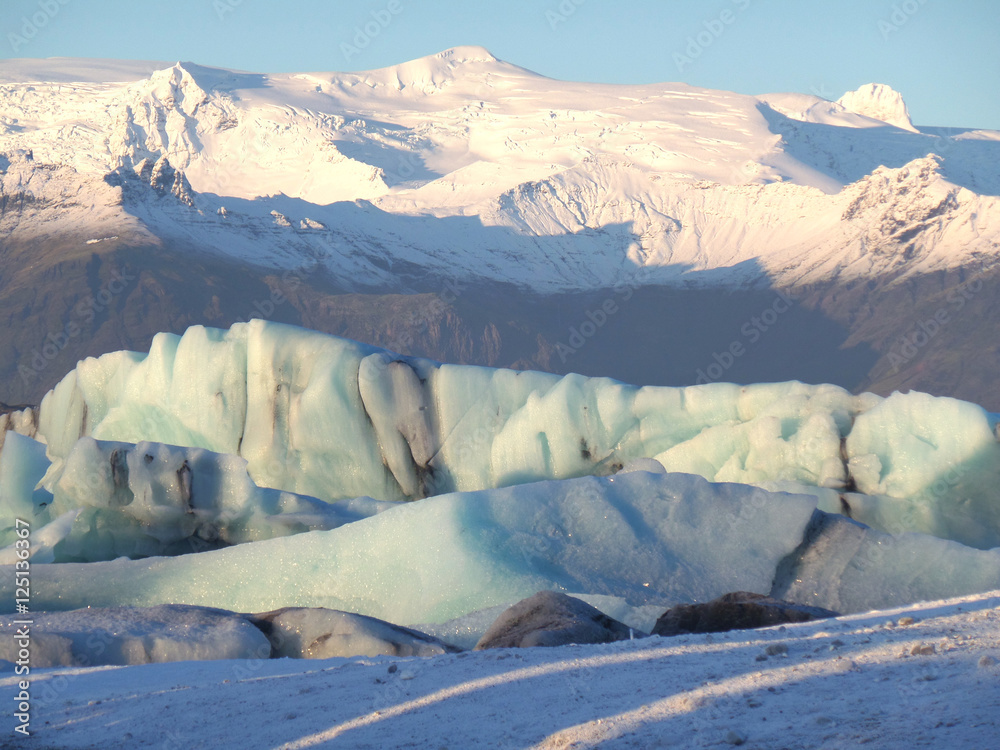 Huge icebergs floating against the snow capped mountain in Vatnajokull National Park in South Iceland Huge icebergs floating against the snow capped mountain in Vatnajokull National Park in South Iceland