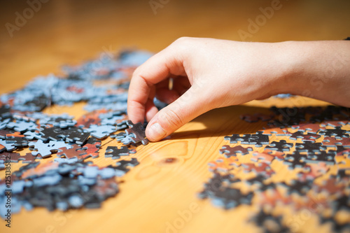 Hand of young girl assembling jigsaw puzzle (color toned image)