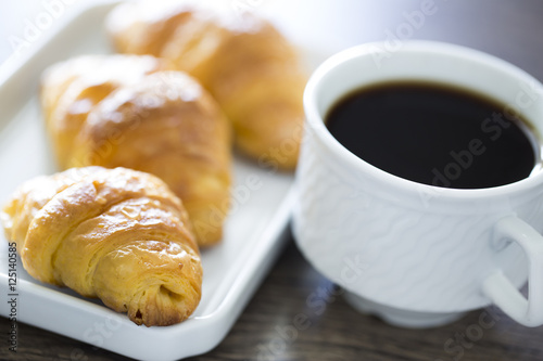 Croissants with coffee on the wooden table. Office workplace