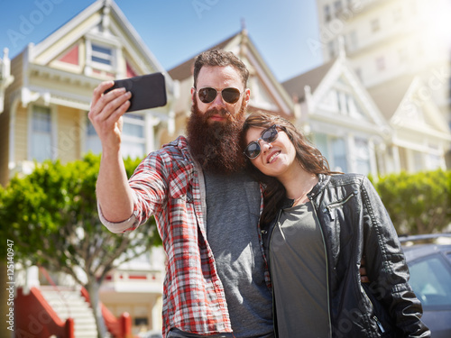 Photography couple taking selfie in front of painted ladies in san francisco