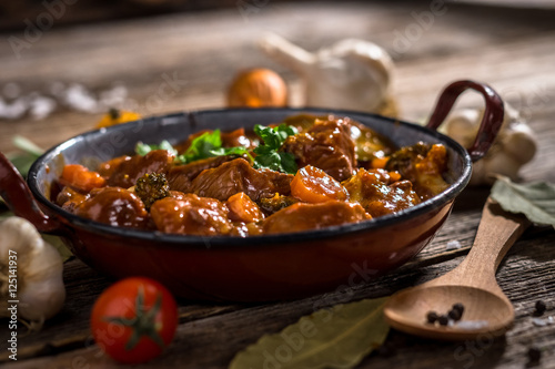 Meat stewed with vegetable on rustic wooden background