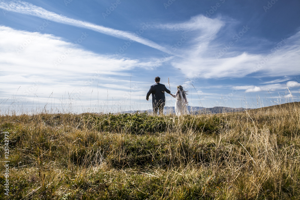Bride and groom run across the mountain