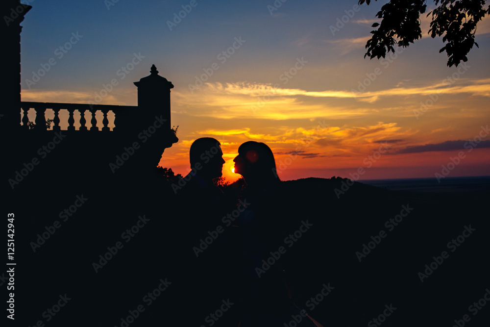 Romantic wedding couples kiss at sunset