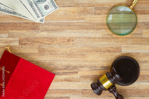 Wooden Law Gavel with legal book, dollar bills and looking glass