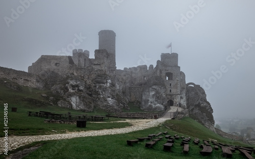 medieval castle ruin sitting on top of hill in heavy fog