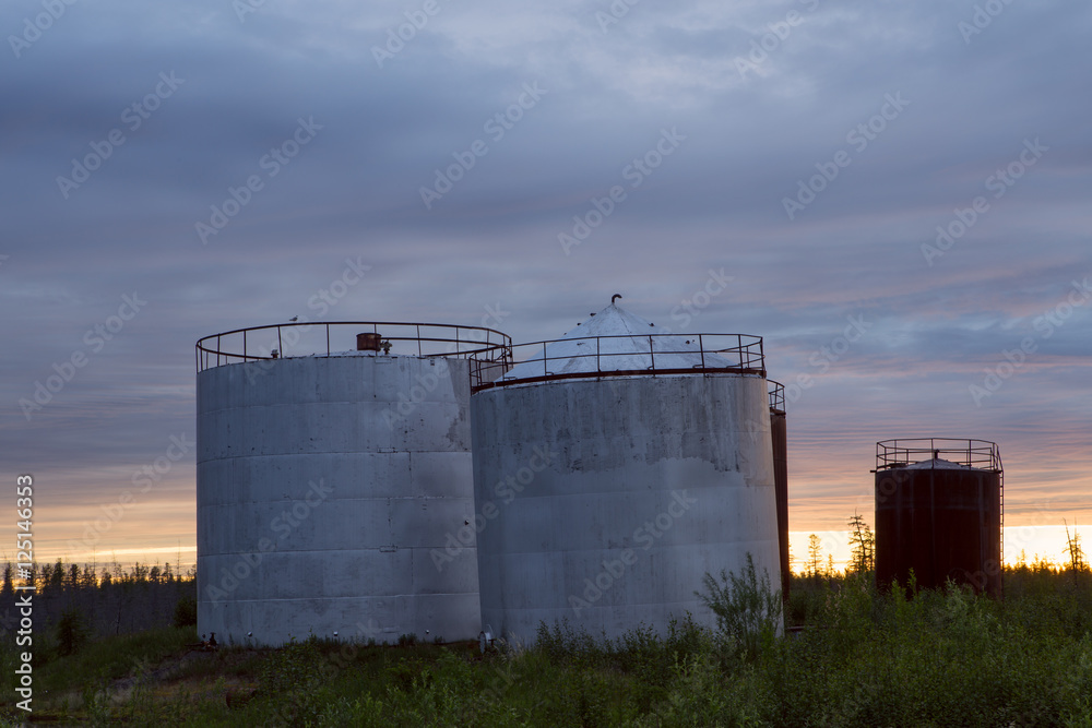 Large tanks at sunset sky background. Indigirka shore. Yakutia. Russia. Large tanks at sunset sky background. Indigirka shore. Yakutia. Russia.