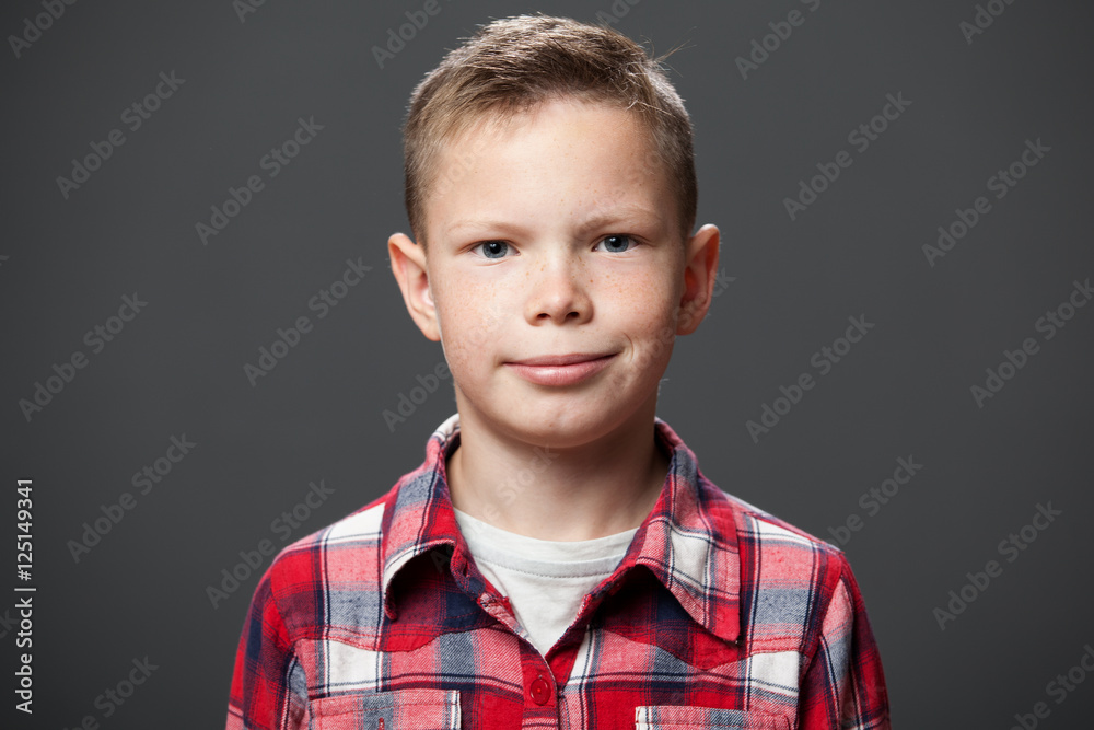 Portrait of a cute smiling boy in a red plaid shirt, gray background Portrait of a cute smiling boy in a red plaid shirt, gray background