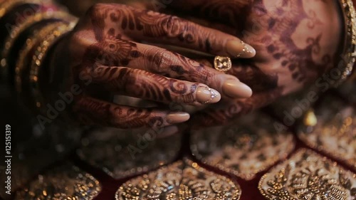 Bride's arms pained with mehndi lie on her red dress with golden design
