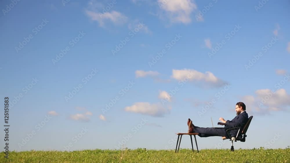 Businessman working on laptop in the field. Thinks about the project.