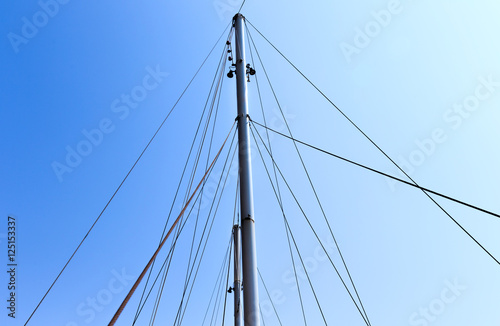 The mast of the ship on a background of blue sky