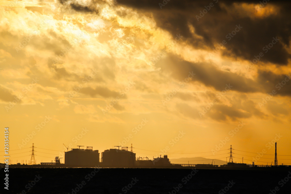 Power plant factory silhouette over sunset at sea
