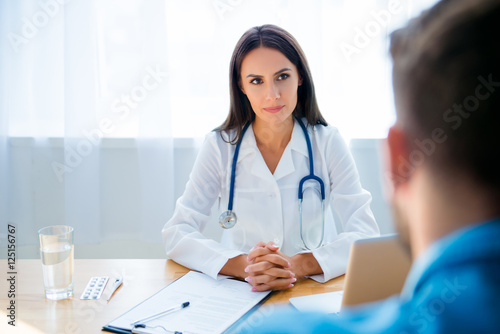 Young female doctor listening and consulting her patient photo